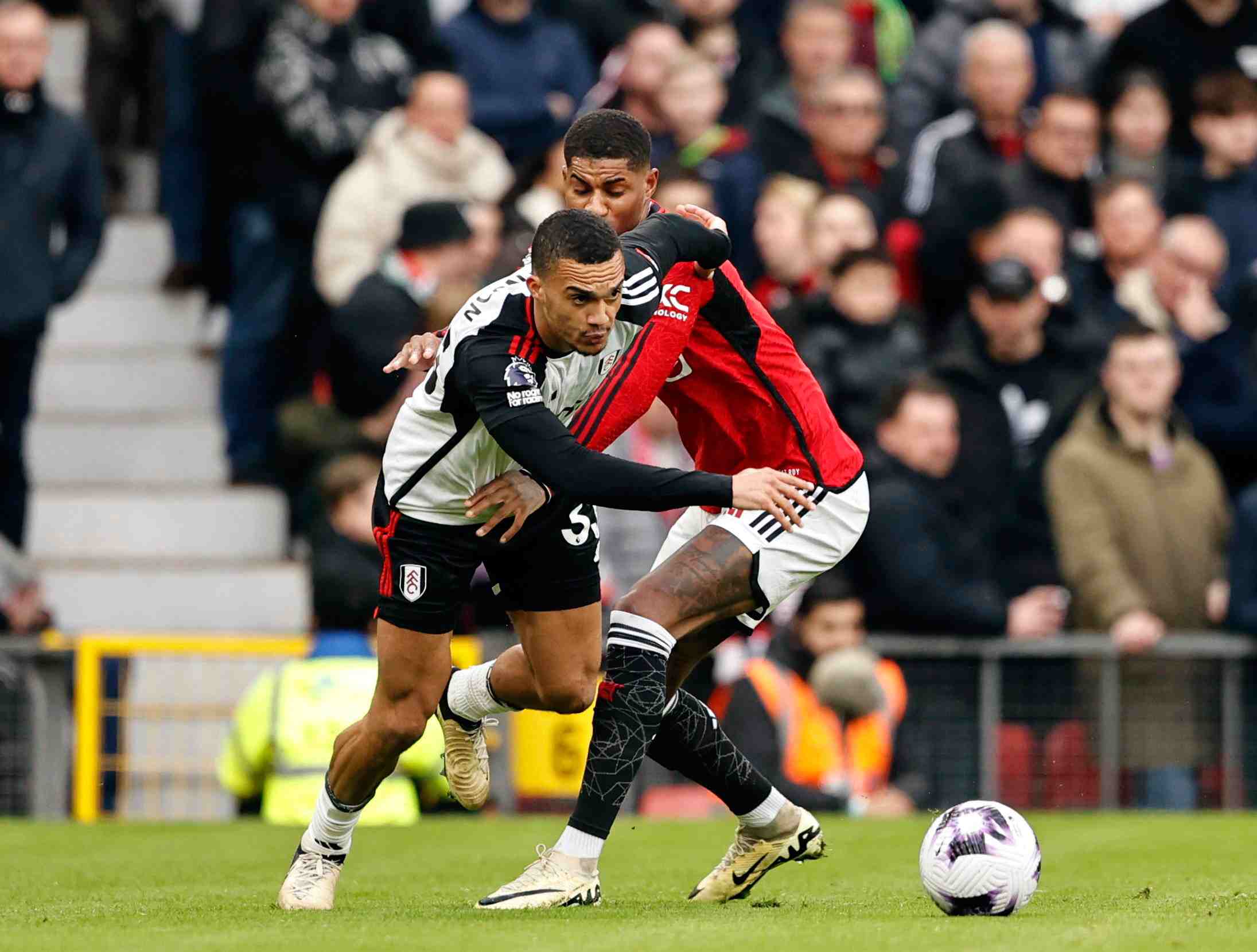 During a 2023/2024 Premier League match at Old Trafford on 24th February 2024, Fulham's Antonee Robinson skillfully maneuvers past Manchester United's Marcus Rashford.
